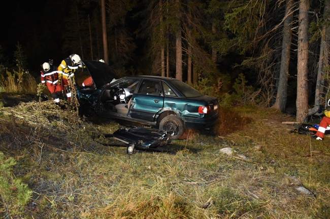 Rettungskräfte beim total beschädigten Auto