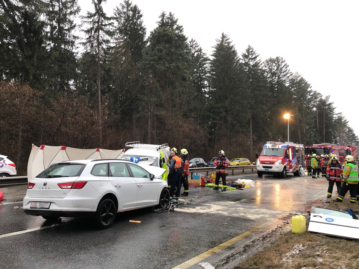 Die beiden total beschädigten Fahrzeuge. Im Hintergrund die Rettungskräfte der Feuerwehr