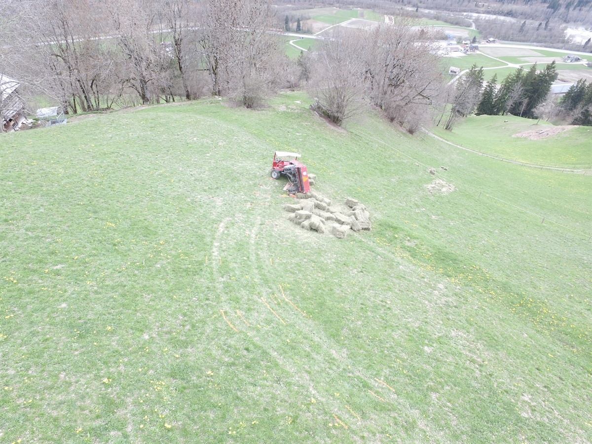 Luftaufnahme von hinten mit dem Fahrzeug in Endlage und abgeworfenen Strohballen.
