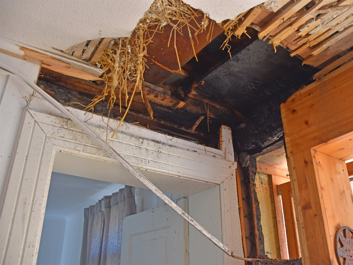 Durch die Feuerwehr geöffnete Wand- und Deckenverschalung. Sichtbare Verkohlung der Holzkonstruktion mit Wärmedämmung aus Stroh.