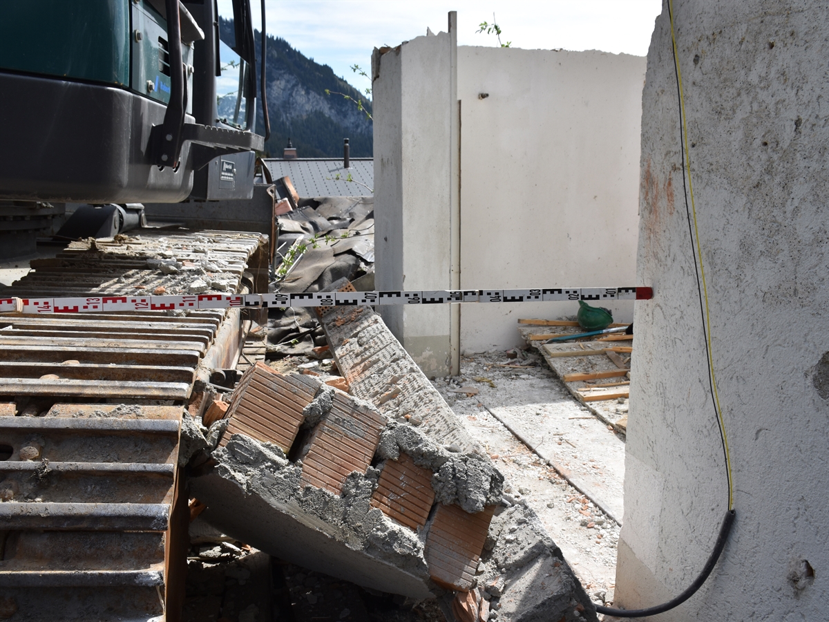 Baustelle mit Bagger und heruntergefallenem Garagentorsturz.