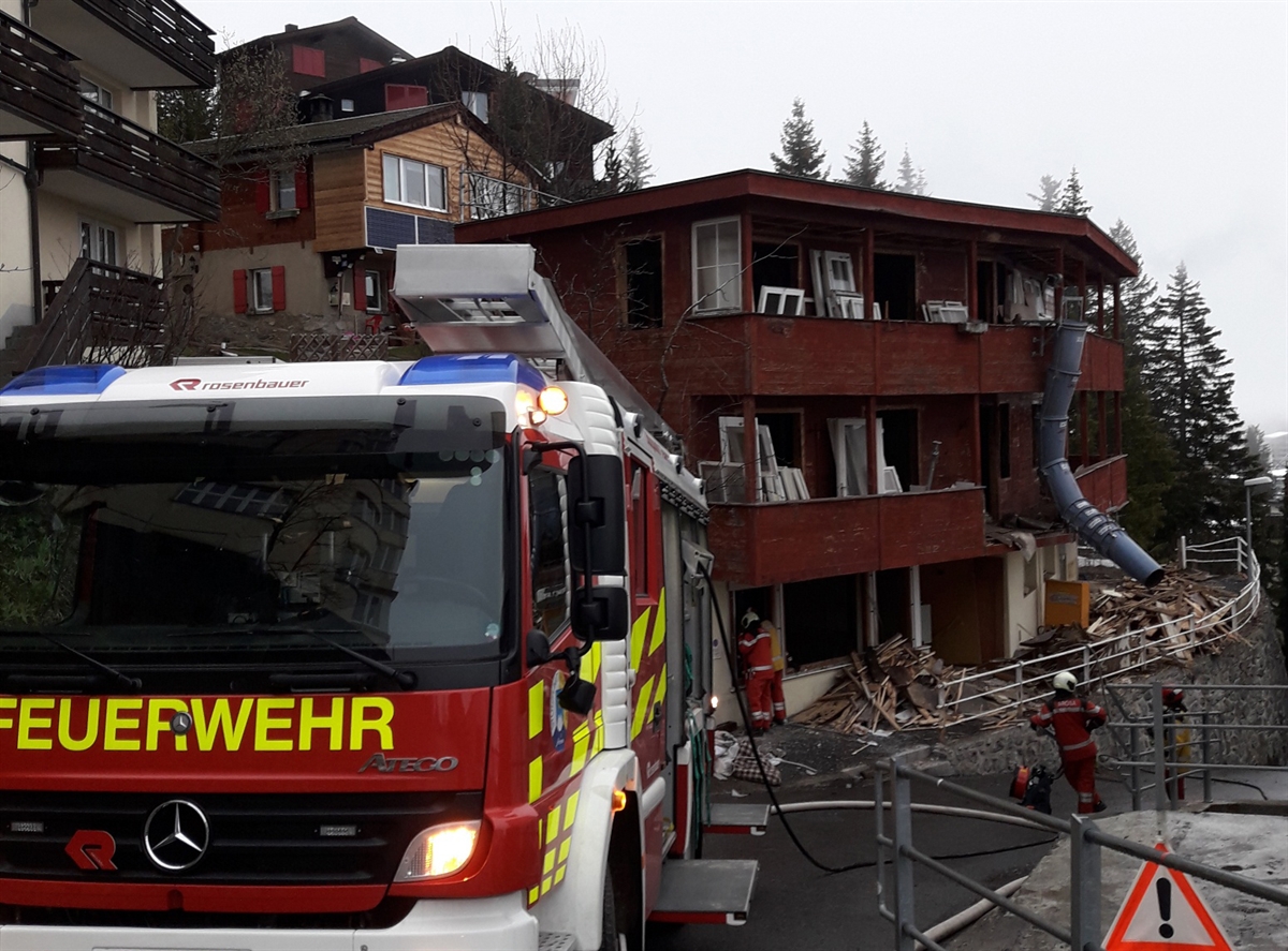 Feuerwehrleute und Tanklöschfahrzeug vor dem Mehrfamilienhaus