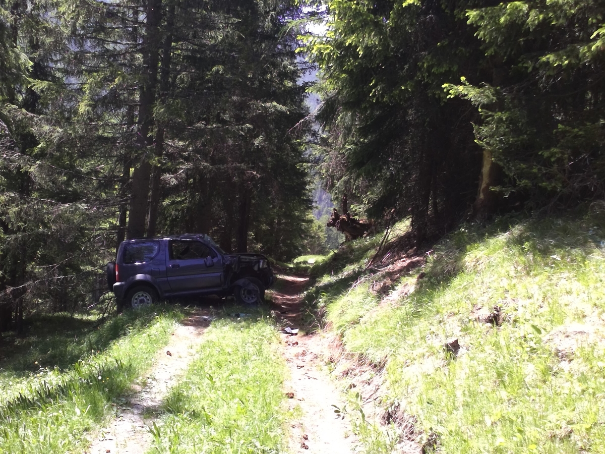 Das total beschädigte Auto steht auf den Rädern quer auf dem Feldweg.