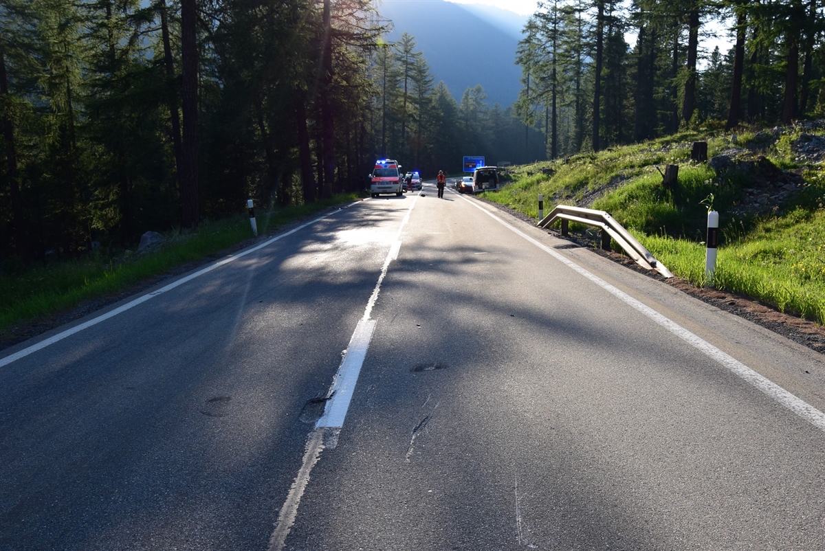 Blick auf die Unfallstelle. Links und rechts der Strasse Wald. Auf der Strasse Rettungsfahrzeug und rechts an der Strasse ein Polizeiauto.