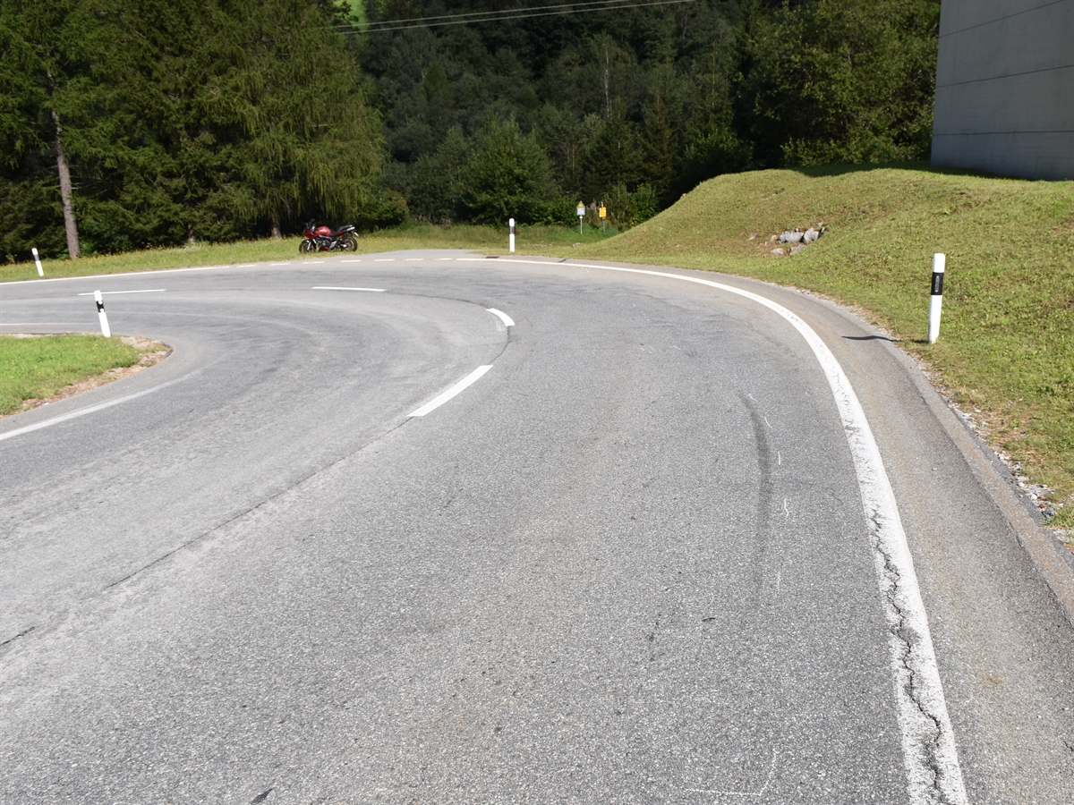 Linkskurve mit verunfalltem Motorrad im Wiesland stehend.