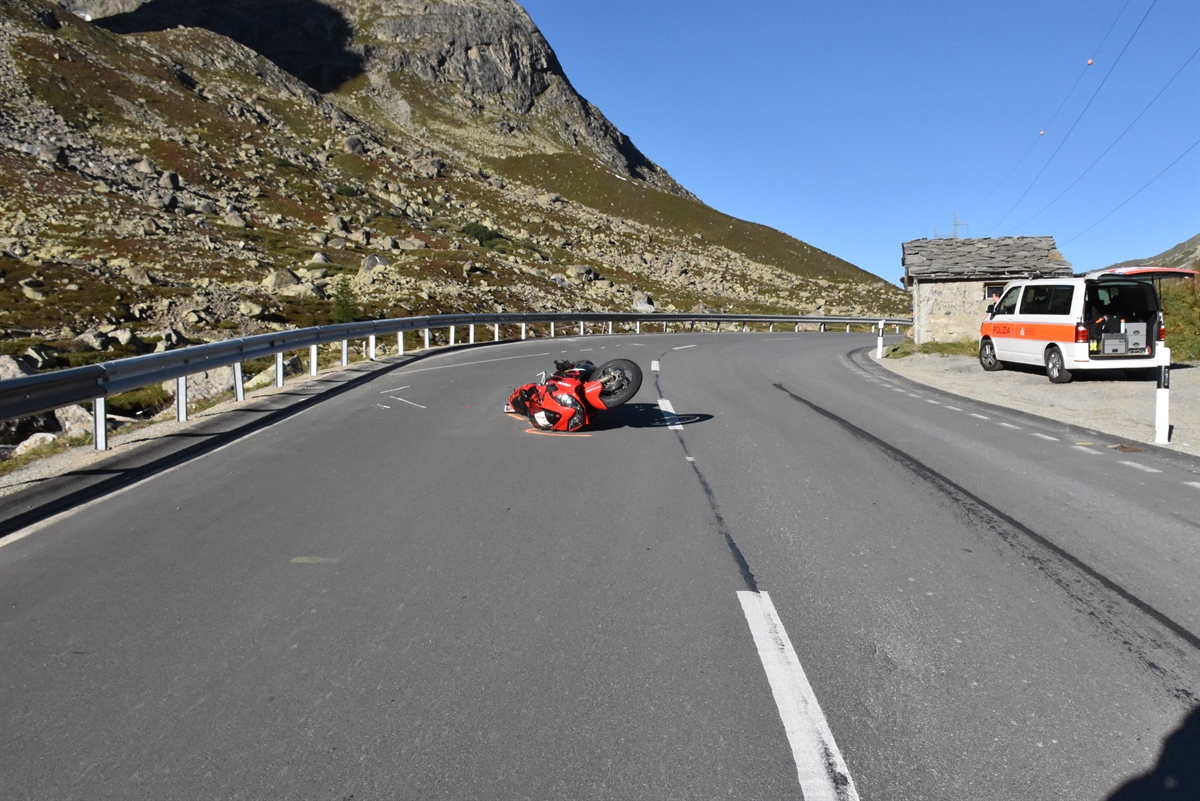 Die Julierstrasse bergwärts gesehen. Links die Leitplanke, rechts davon das auf der Strasse liegende Motorrad. Rechts auf einem Ausstellplatz ein Patrouillenwagen.