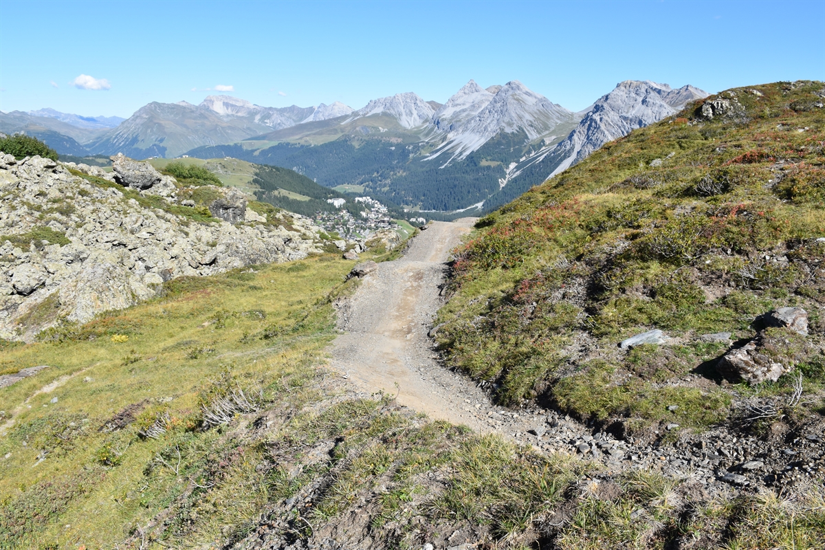 Der kuppierte Flowtrail in Fahrtrichtung gesehen. Im Hintergrund Himmel und Berge.