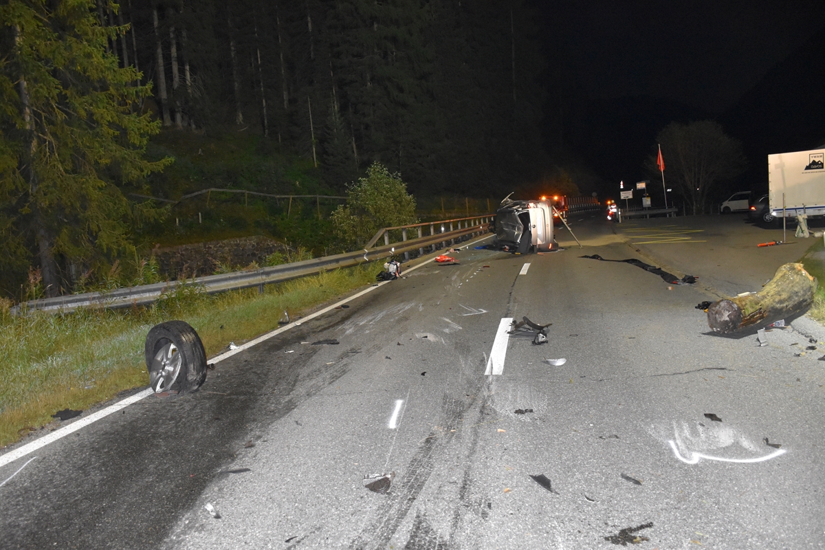 Die Unfallstelle in Fahrtrichtung gesehen. Mitten auf der Strasse das auf der linken Seite liegende Auto. Auf der Fahrbahn einige Trümmerteile.