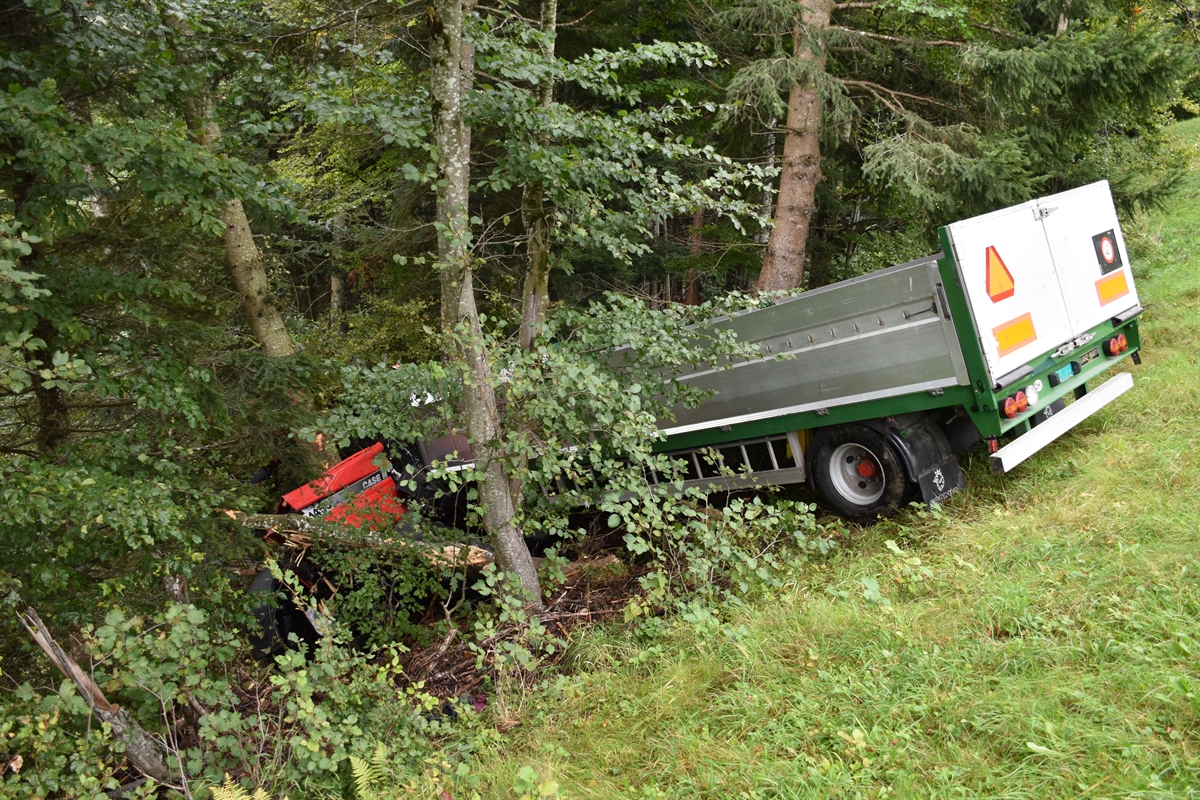 Links der total beschädigte Traktor in den Bäumen. Rechts davon der Anhänger.