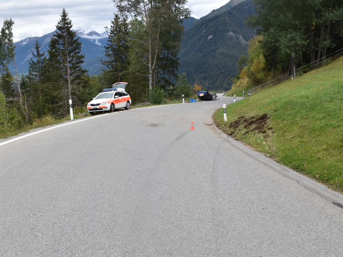 Unfallörtlichkeit mit dem Unfallfahrzeug auf dem Dach liegend im Hintergrund