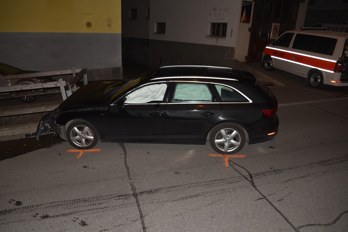 Seitenaufnahme des Autos von links. Die Front am Bündnerzaun. Gut sichtbar die ausgelösten Airbags. Rechts davon ein Polizeiauto.  