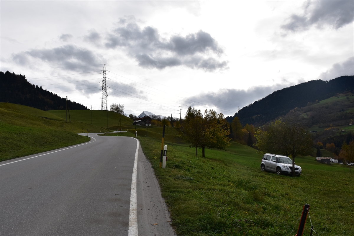 Situation bergwärts gesehen: Rechts das Auto, welches mit der Front auf einer Wiese an einem Apfelbaum steht. Links davon die Strasse, welche sich den Berg hochschlängelt. Links davon wiederum eine Wiese.