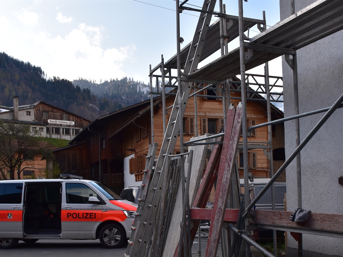 Gerüst am Haus mit angestützter Leiter. Patrouillenwagen der Kantonspolizei im Hintergrund.