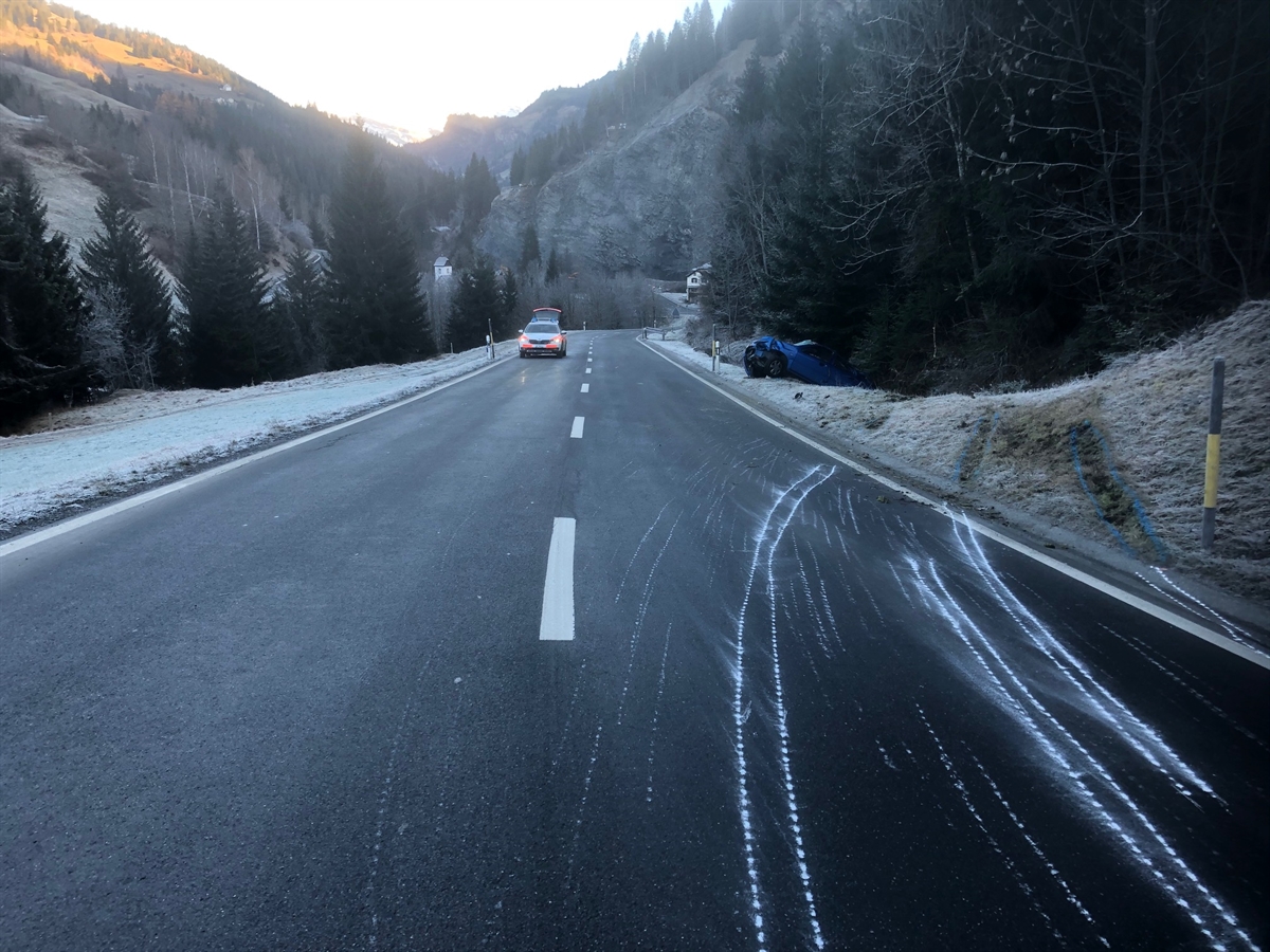 Schleuderspuren auf der Valserstrasse, welche ins angrenzende Wiesland/Böschung weiterverlaufen. Neben der Strasse auf den Rädern stehendes total beschädigtes Auto.