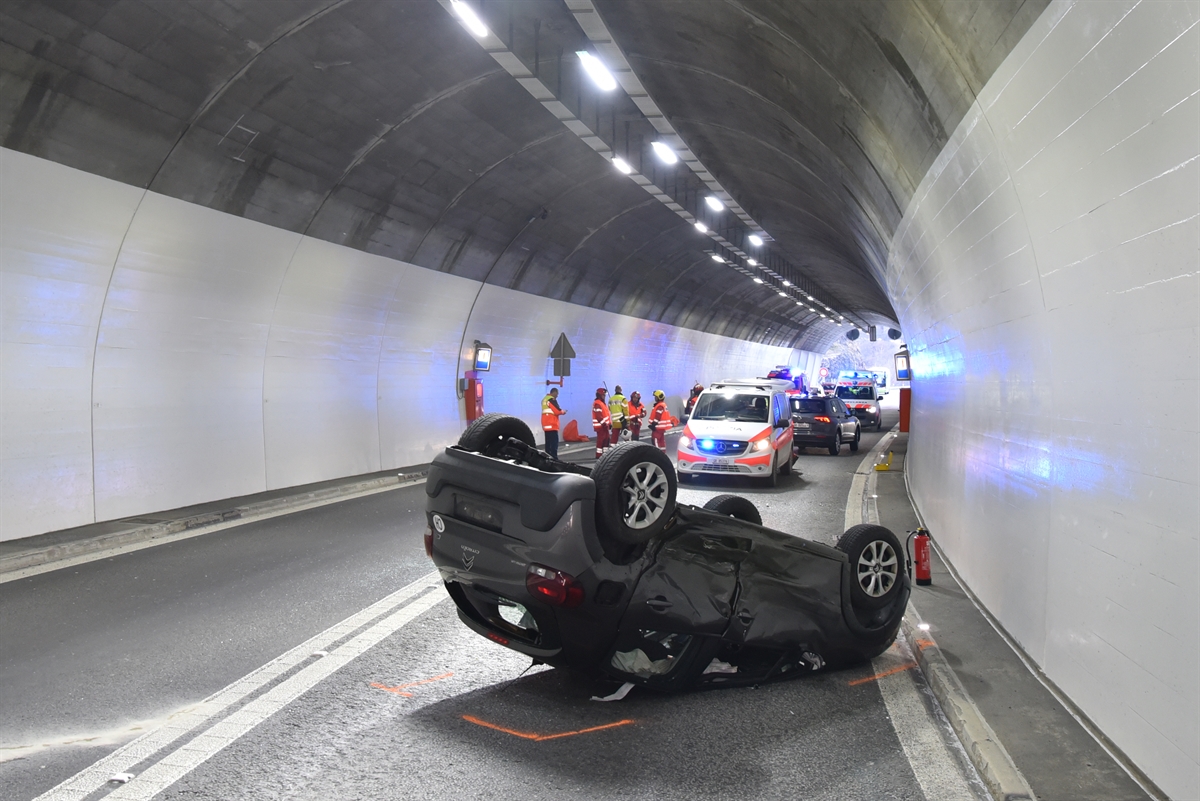 Auto liegt auf dem Dach. Im Hintergrund ein Polizeiauto und Rettungskräfte