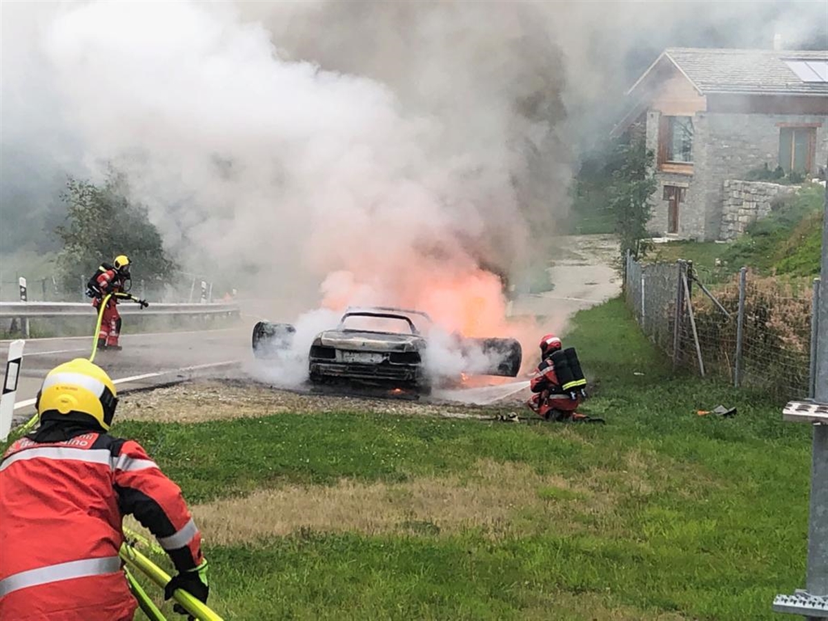 Fahrzeug brennt auf Ausstellplatz. Feuerwehrleute im Einsatz