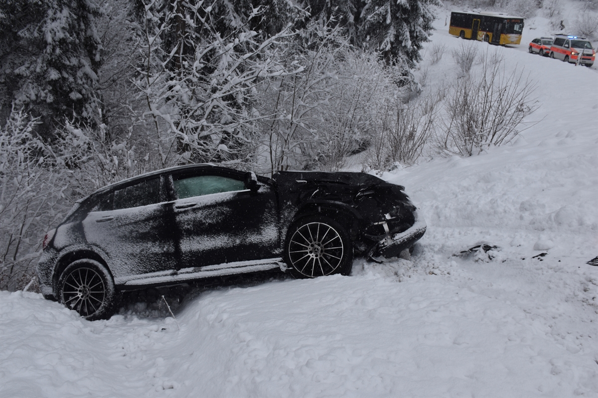 Das talwärts fahrende Auto in der abfallenden Böschung. Rechts davon die Strasse mit zwei Polizeiautos und einem Postauto.