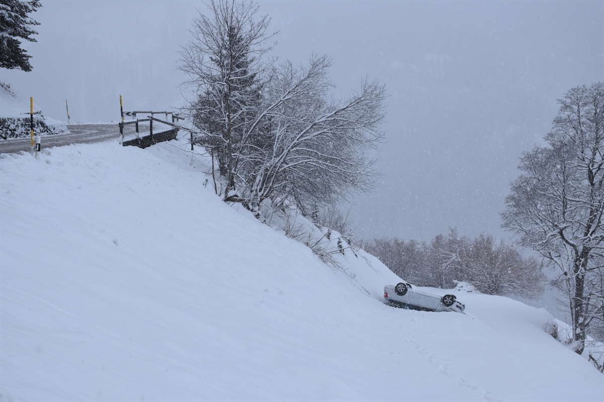Auto liegt im schneebedeckten Abhang auf dem Dach