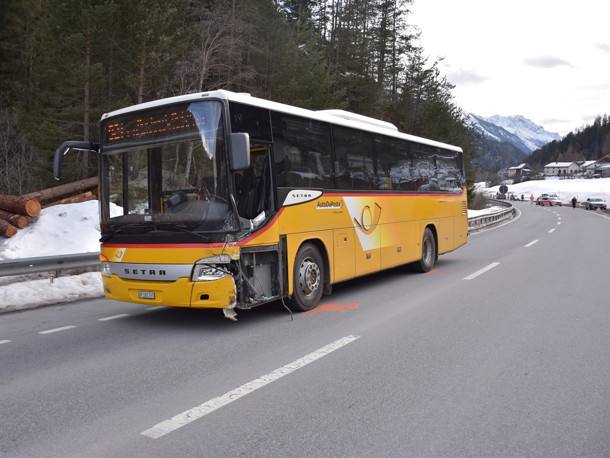 Das vorne links beschädigte Postauto steht links auf der Fahrbahn. Im Hintergrund ein Polizeiauto und verschiedene Einsatzkräfte.