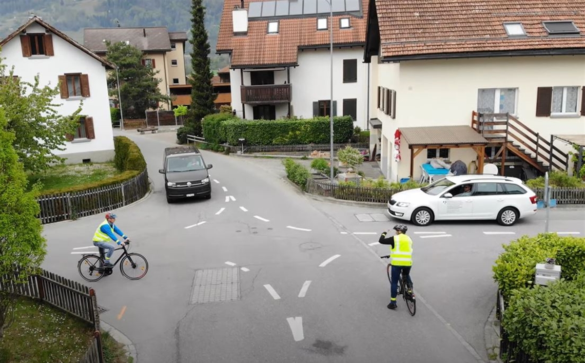 Blick von der Drohne auf eine Kreuzung mit zwei Velos und zwei Autos