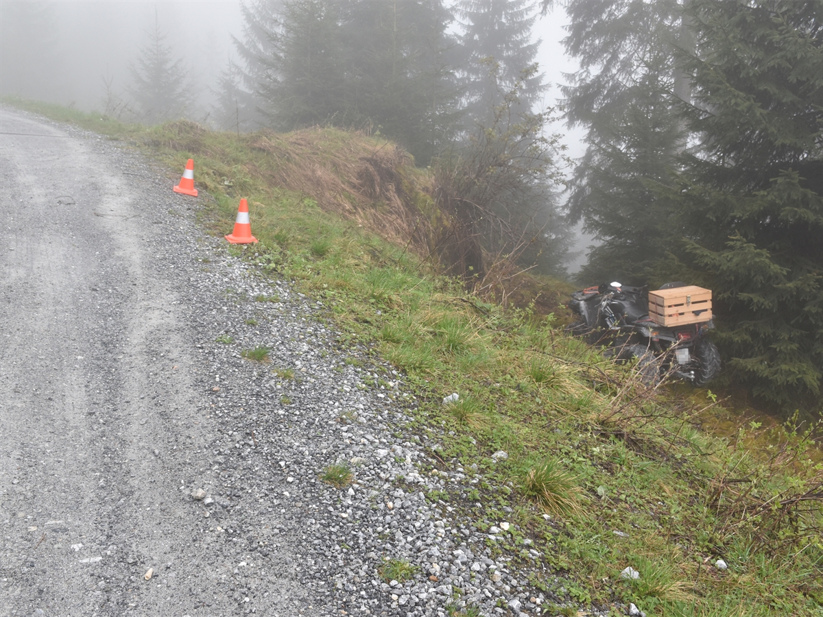 Am linken Bildrand die Bergstrasse. Rechts davon die abfallende Böschung und der auf den Rädern stehende Quad. Unter diesem war der Mann eingeklemmt und gefangen.