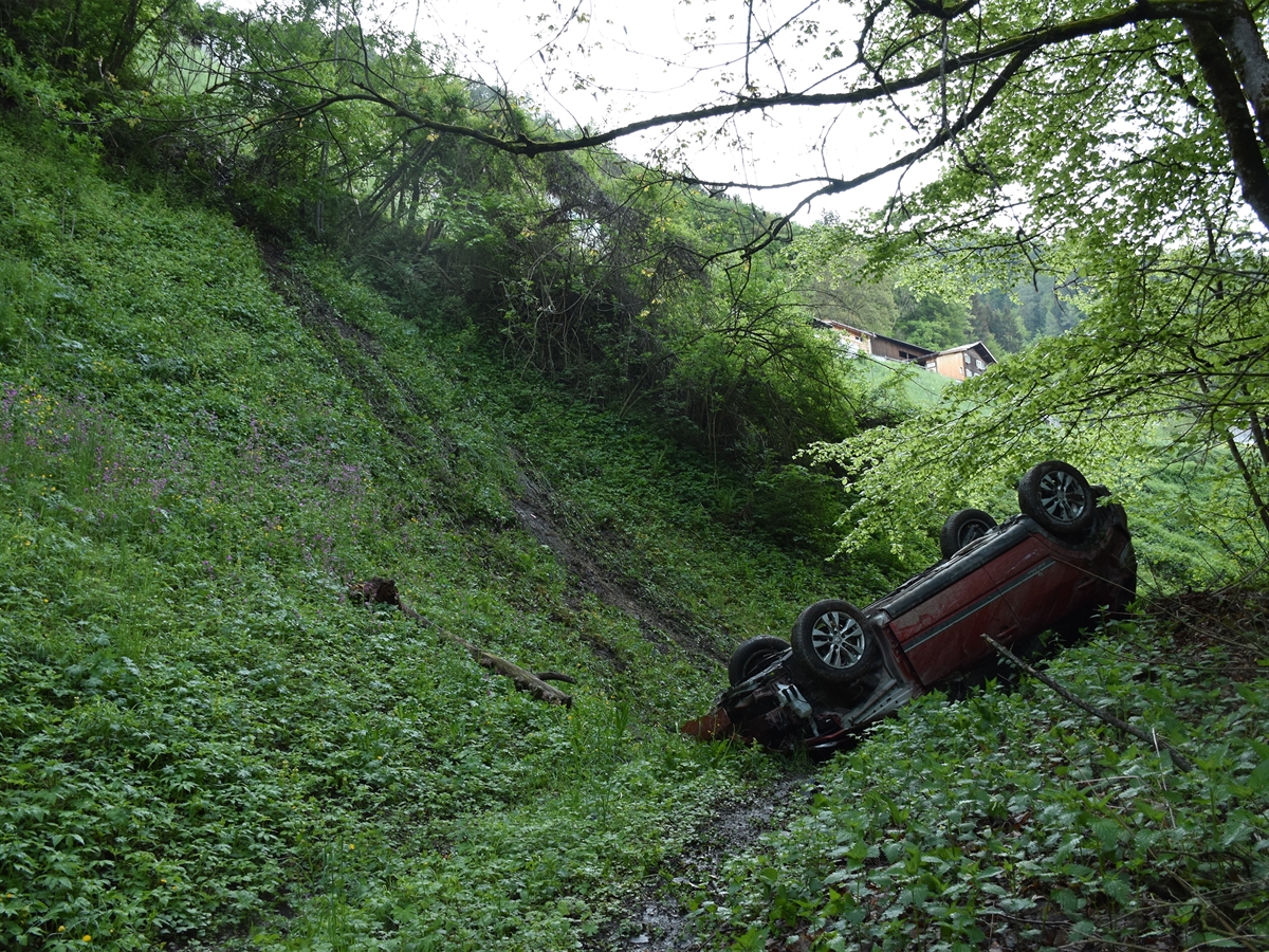 Das auf dem Dach liegende Auto am Fusse eines Abhangs.