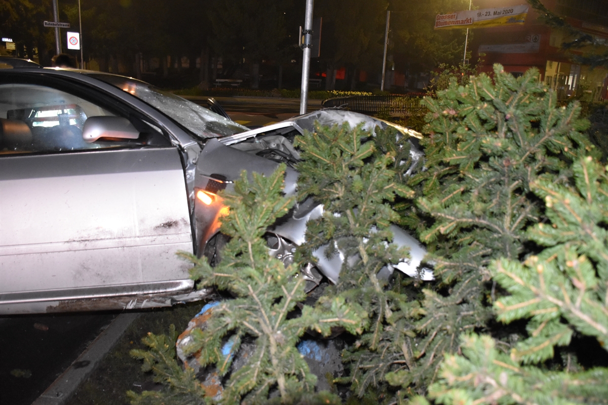 Nachtaufnahme, links ein Teil einer Verzweigung, rechts davon am rechten Strassenrand das total beschädigte Auto, welches mit der Front auf einem Steinblock steht. 