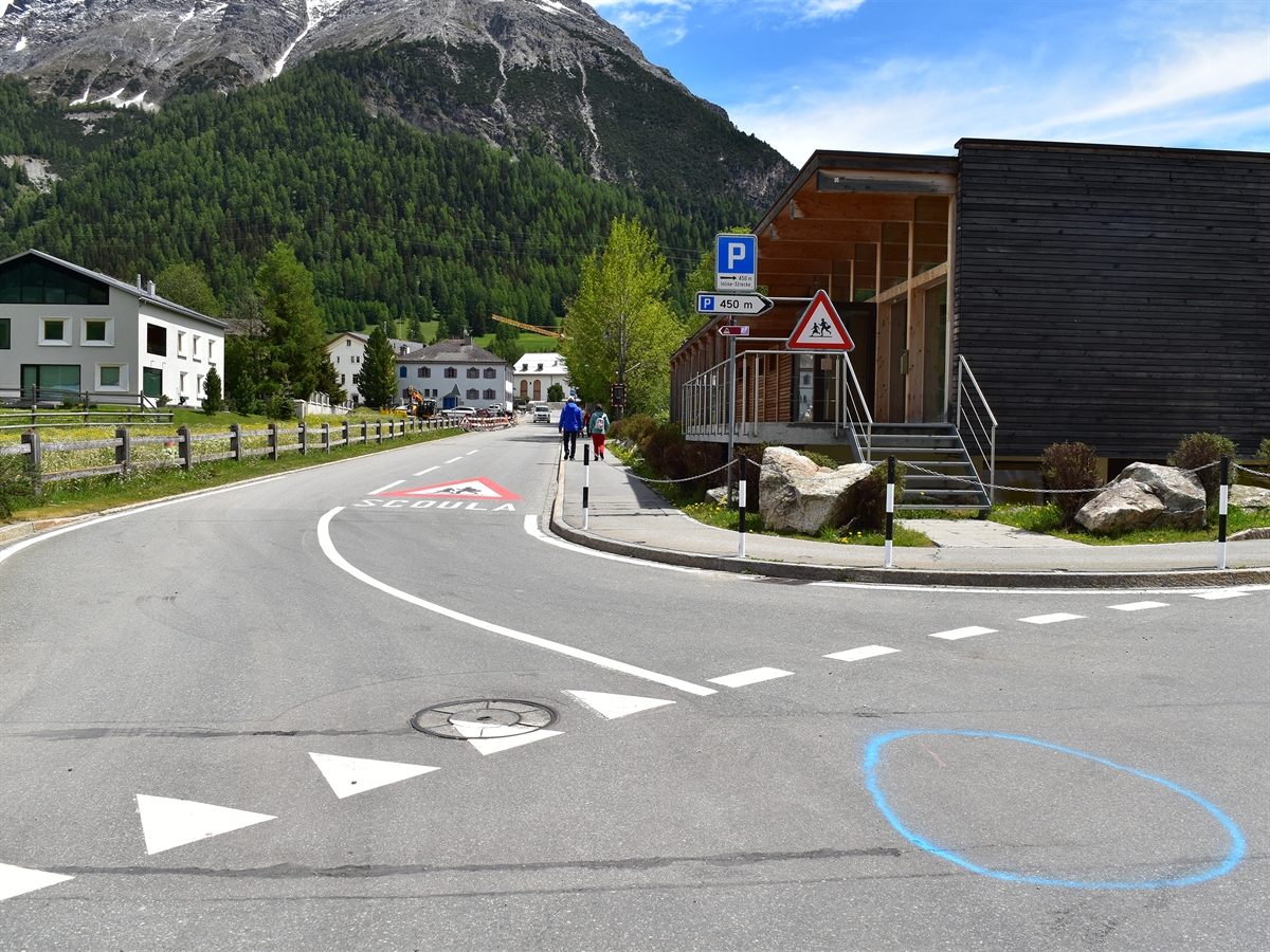 Die Verzweigung der Via Cumünela mit der Seitenstrasse. Mit einem blauen Kreis wurde die Kollisionsstelle auf der Fahrbahn markiert.