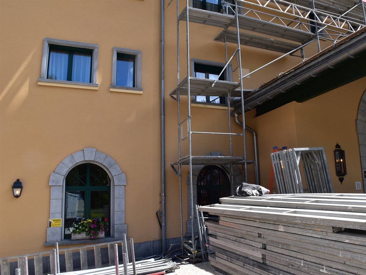 Hausfassade mit einem zu demontierenden Gerüst. Auf dem Hausvorplatz stehen Gerüstelemente zum Abtransport bereit