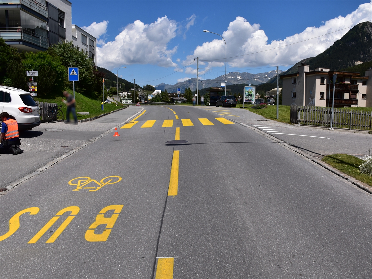Talstrasse im Bereich der Unfallstelle. Links der Schiaweg mit dem Unfallauto, dem Fahrrad und einem knienden Polizisten.