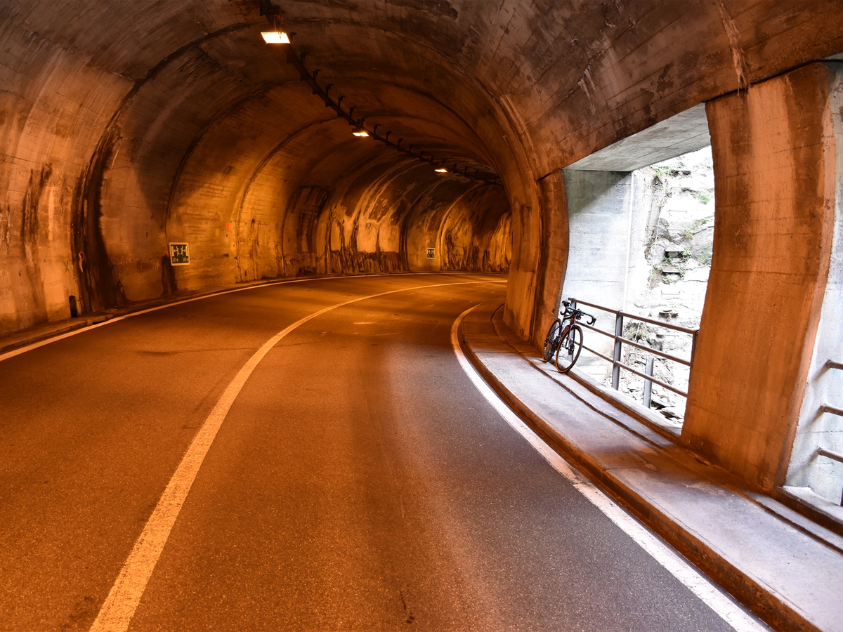 Der Tunnel Ruinas. Auf der rechten Fahrbahnseite steht auf dem Trottoir das Rennrad an einem Geländer angelehnt.