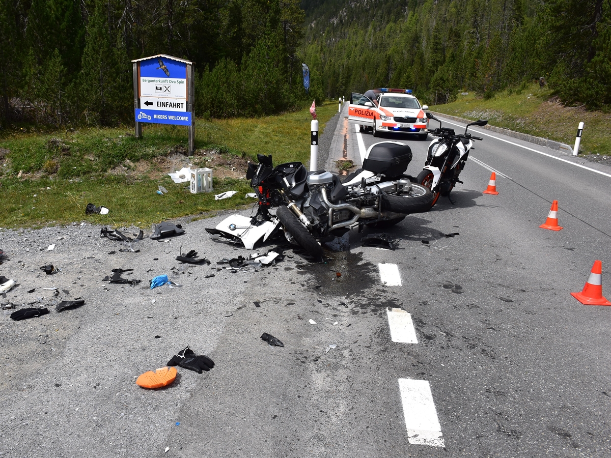 In der Bildmitte das total beschädigte Motorrad und Trümmerteile. Im Hintergrund das Motorrad, welches rechtzeitig zum Stillstand kam. Weiter im Hintergrund ein Polizeiauto.