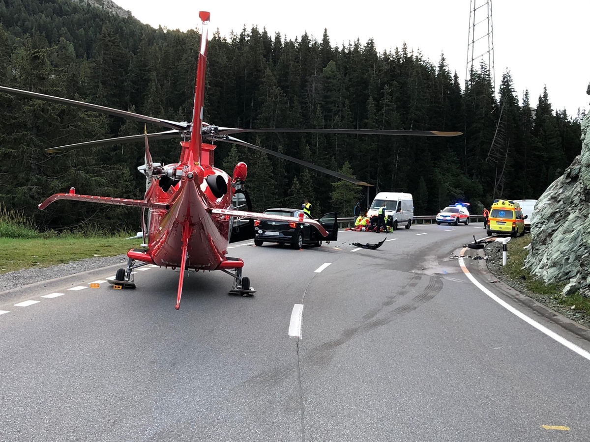 Der Rega-Helikopter mitten auf der Strasse. Dahinter die involvierten Fahrzeuge, Kollisionsspuren auf der Bergfahrbahn und etwas weiter weg ein Polizeiauto.
