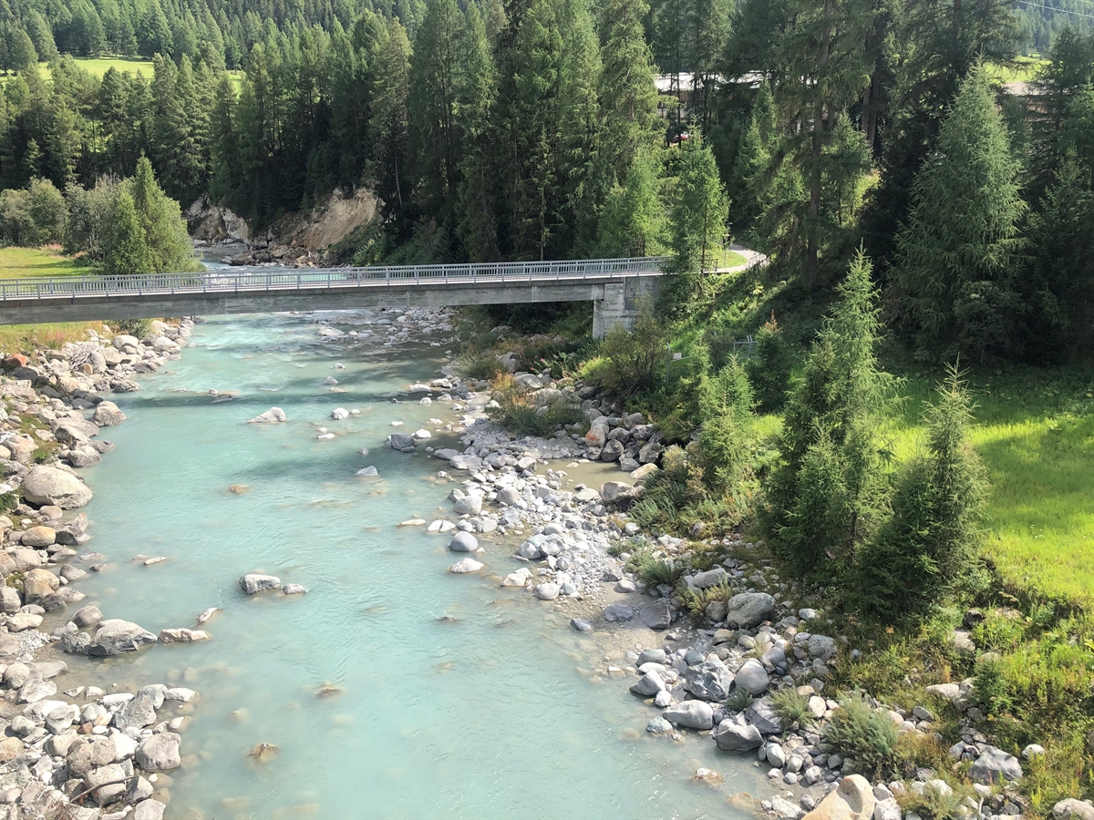 Luftaufnahme von schräg oben auf den Inn, umsäumt von Bäumen. Eine Brücke, die über den Inn verläuft.