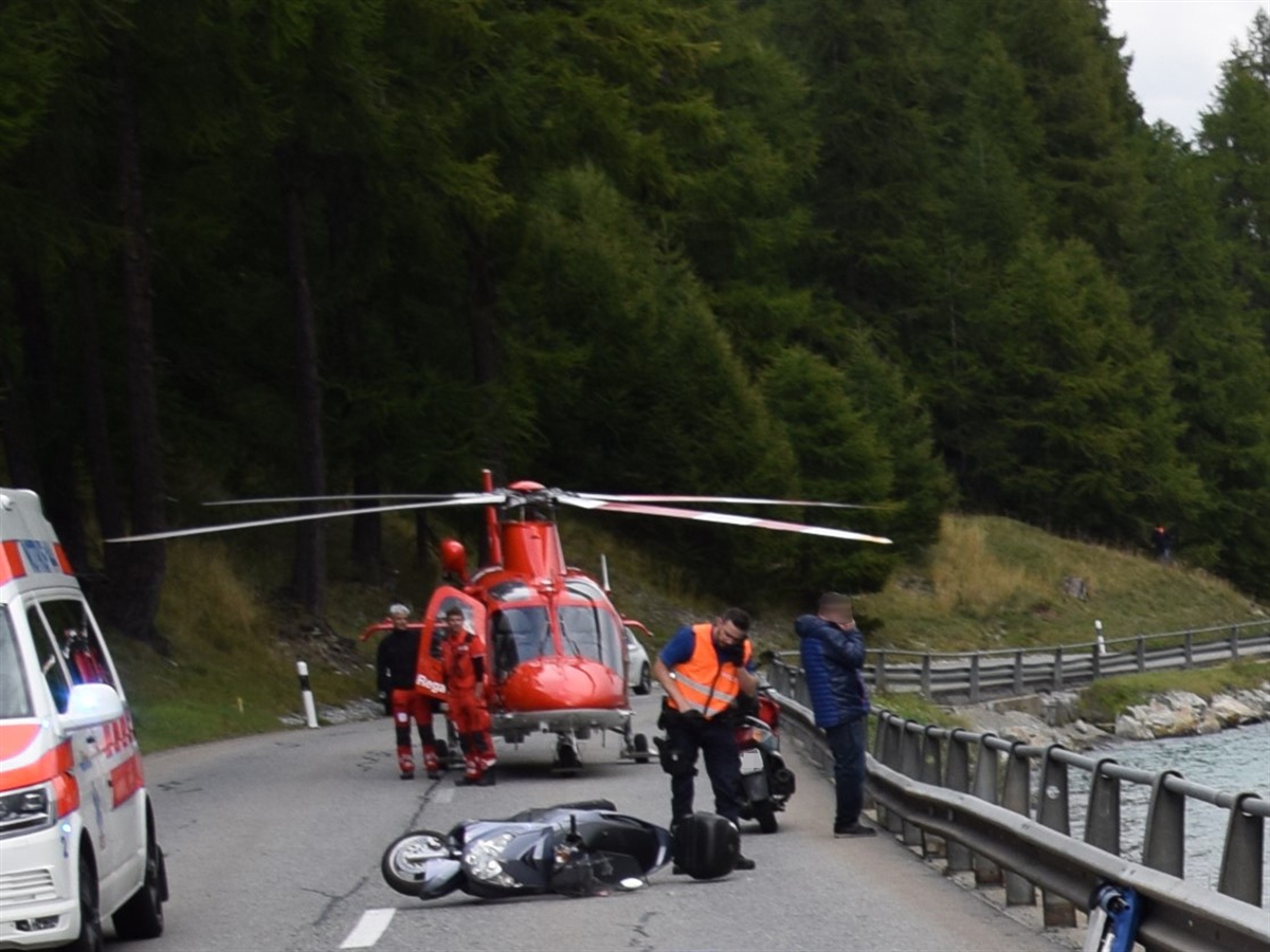 Rechts der See, links davon die Strasse mit dem am Boden liegenden Motorrad. Links davon eine Ambulanz. Im Hintergrund Einsatzkräfte und der Rega-Helikopter.