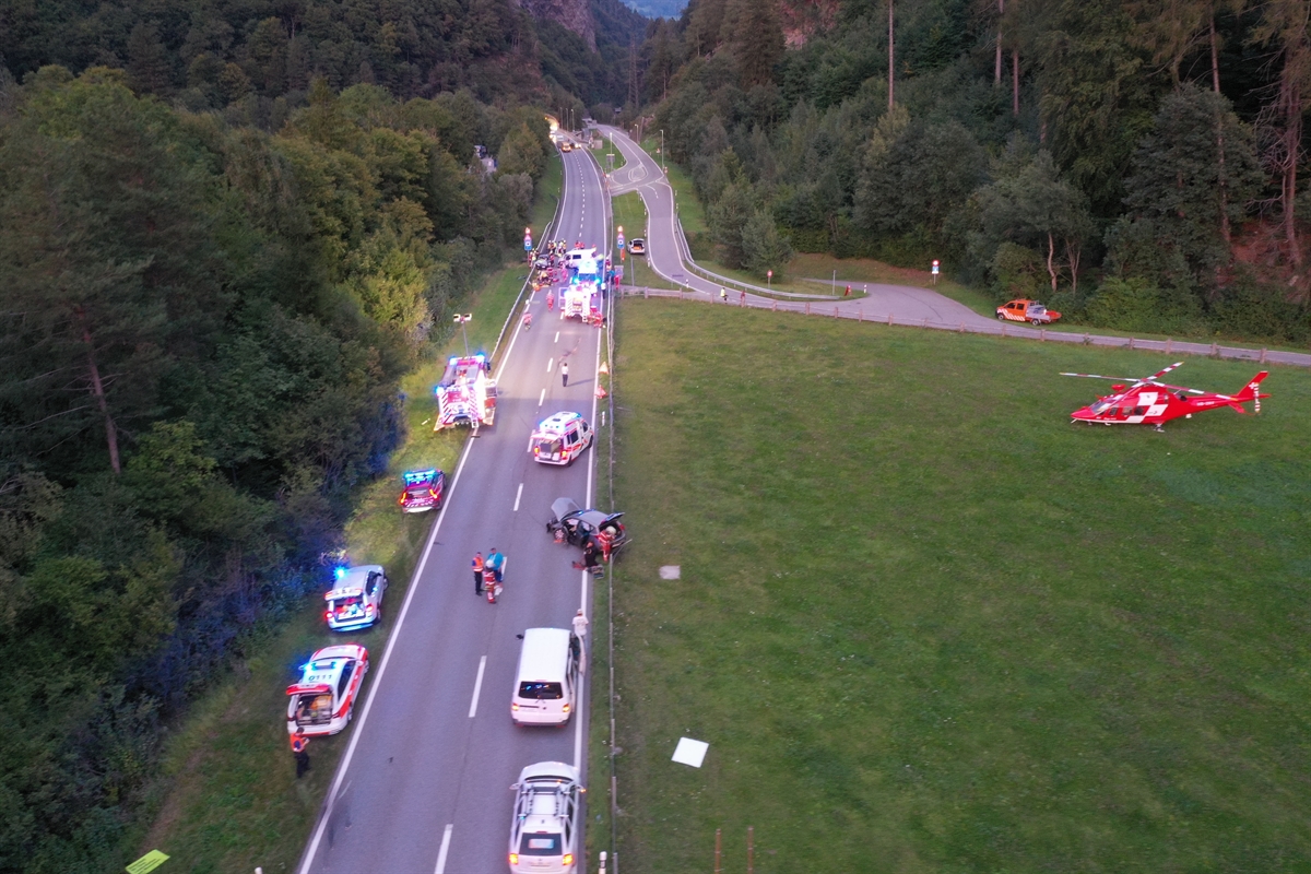 Luftaufnahme auf die Unfallstelle. Entlang der Prättigauerstrasse einige Einsatzfahrzeuge sowie die kollidierten Fahrzeuge. Rechts in der Wiese der Rega-Helikopter.