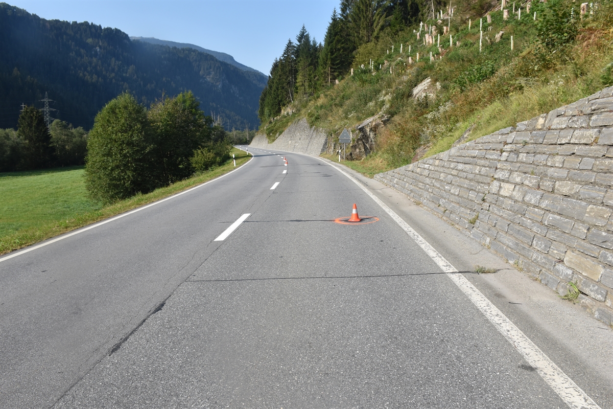 Oberalpstrasse mit übersichtlicher Linkskurve in Richtung Disentis gesehen. Unfallstelle auf der Fahrbahn gekennzeichnet mit roter Farbe und einem Molankegel.