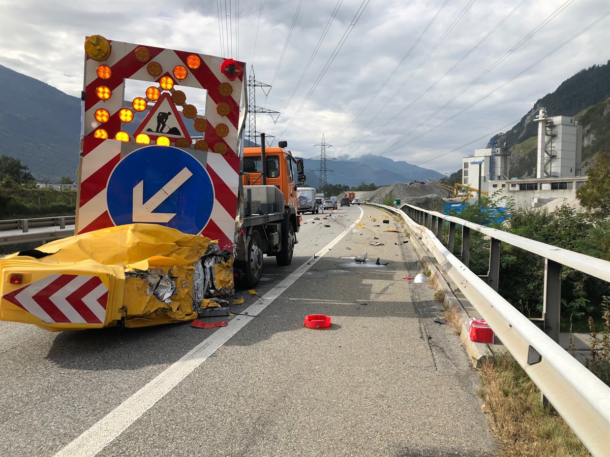 Blick vom Pannenstreifen leicht nach links auf die A13. Im Vordergrund auf der Normalspur der Signallastwagen mit stark beschädigtem Aufpralldämpfer. Kollisionsteile auf der A13.