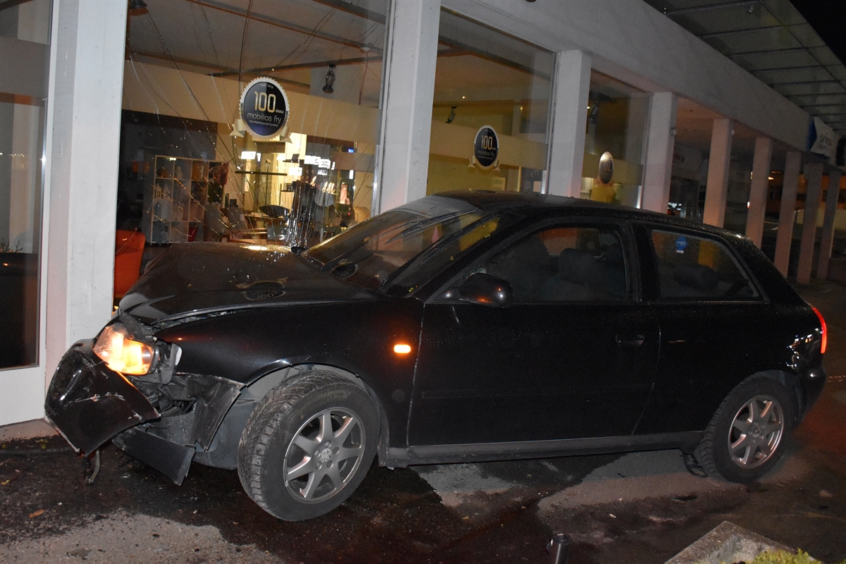 Das kollidierte Auto mit stark beschädigter Front in Endlage an der Gebäudefassade.