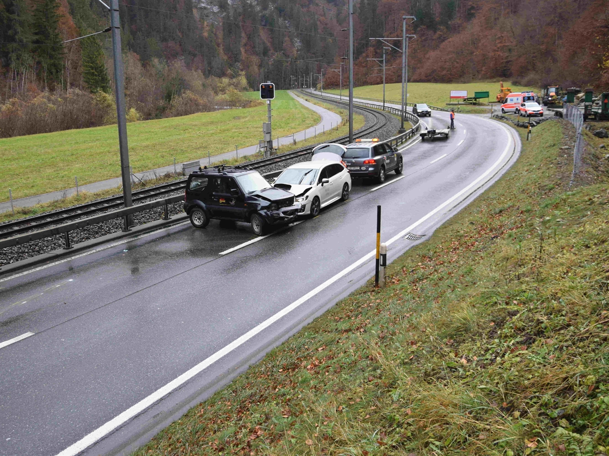 Aufnahme der Strasse von einem Wiesenbord runter. Auf der Strasse quer das geschleuderte Fahrzeug, an dessen rechter Seite das Auto aus der Gegenrichtung. Beide Fahrzeuge beschädigt.