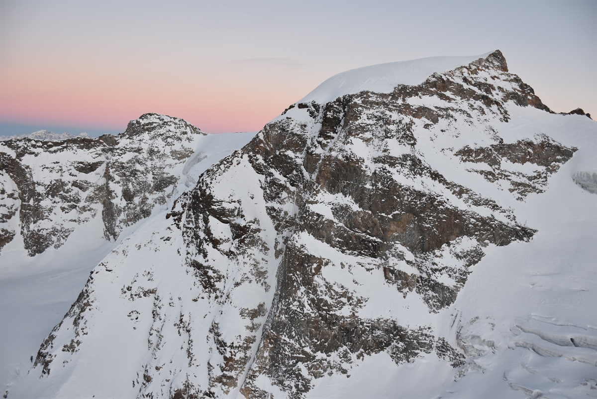 Aufnahme der Nordwestflanke des Piz Cambrena. Im Hintergrund der Horizont mit Abendrot.