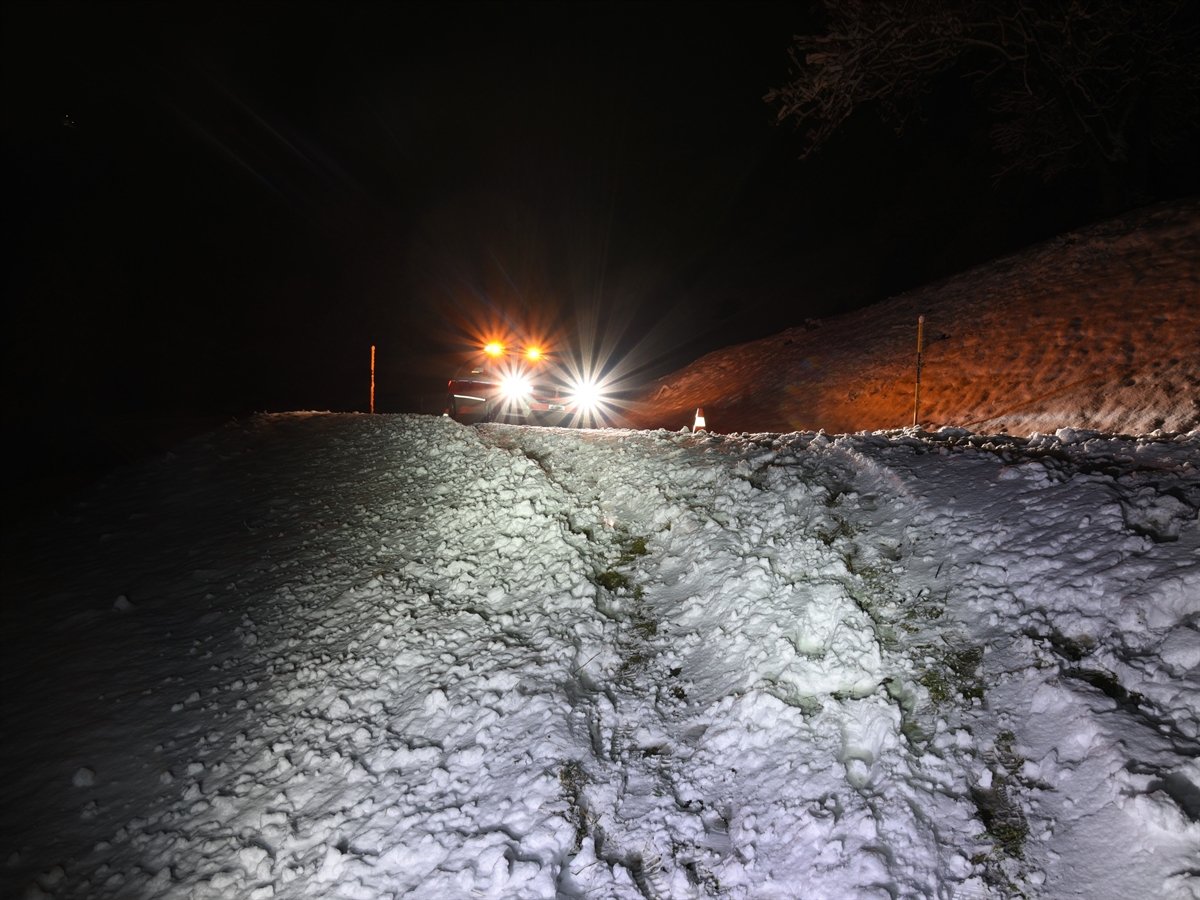 Nachtaufnahme aus einer Böschung auf die Strasse hoch. Dort steht ein Polizeitauto mit gelb blinkenden Leuchten auf dem Dach. Alles ist schneebedeckt. 