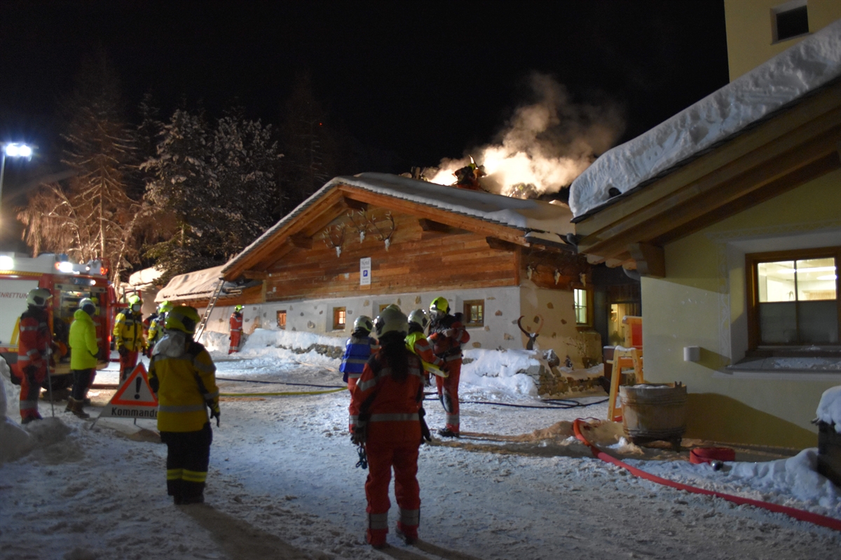 Feuerwehrleute vor dem Gebäude, Rauch steigt aus dem Dach.