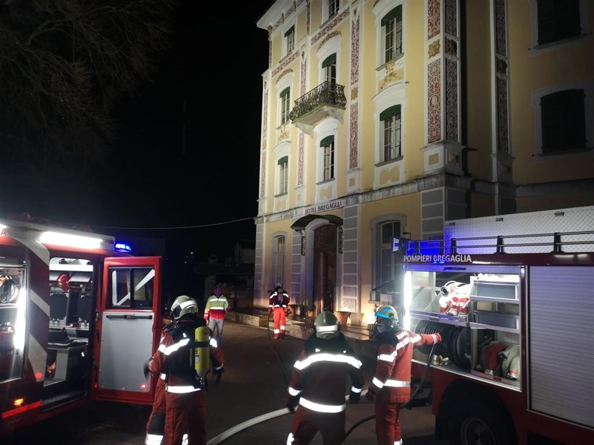 Mehrere Einsatzkräfte der Feuerwehr mit zwei Einsatzfahrzeugen in der Nacht vor dem Hotel.
