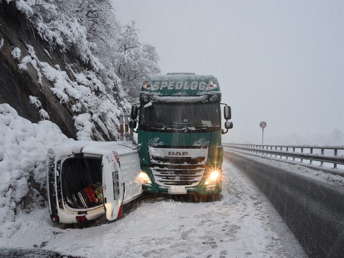 Rechtsseitig neben der Felswand steht ein Lastwagen auf der bergwärts führenden Fahrbahn. Zwischen Felswand und Lastwagen steckt das auf der rechten Seite liegende Fahrzeug.