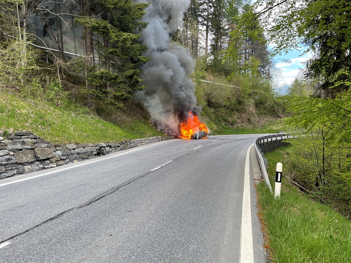 In Bildmitte auf der Hauptstrasse das in Vollbrand stehende Auto.