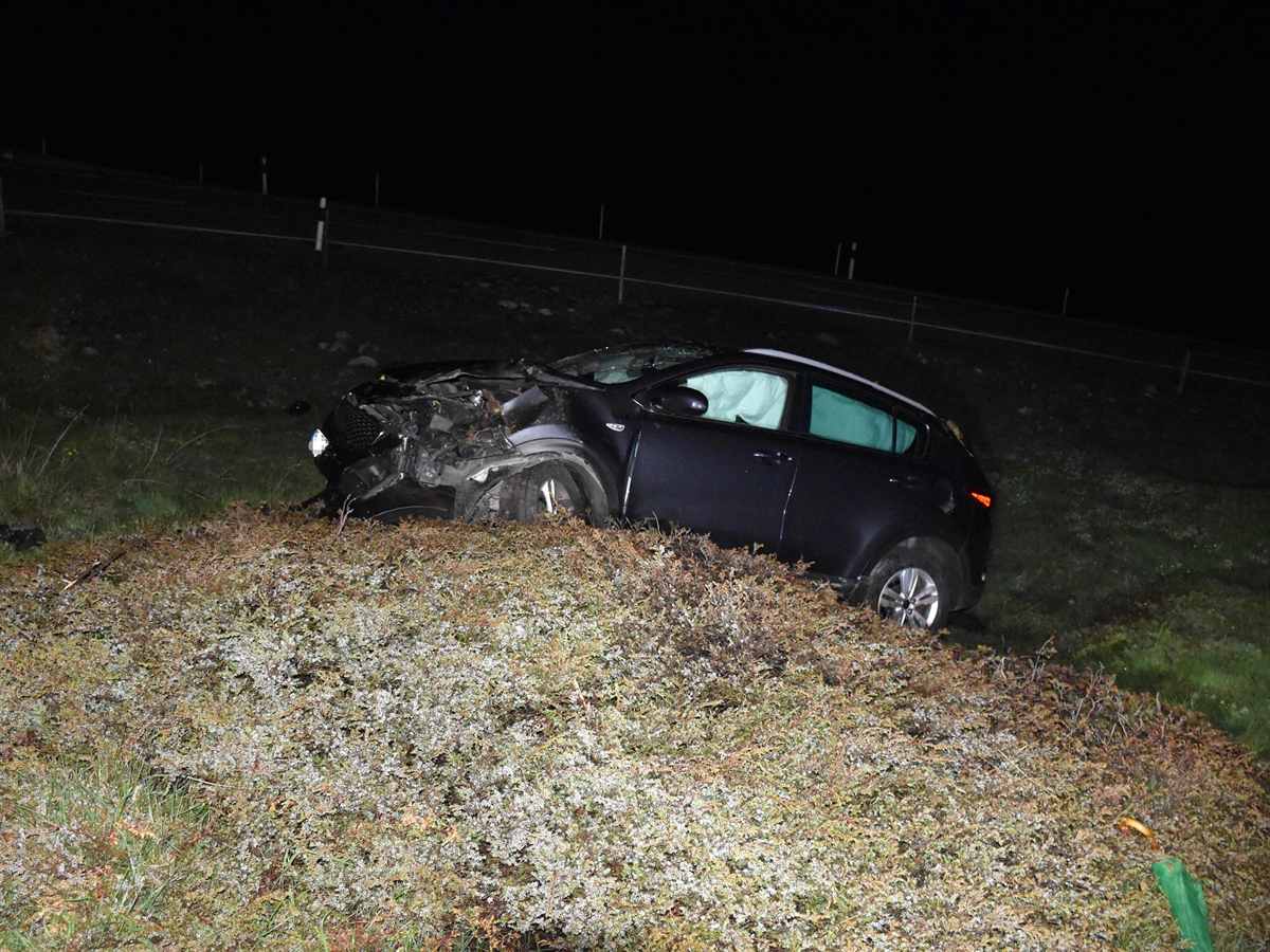 Nachtaufnahme mit total beschädigtem Auto – auffällig die aufgeblasenen Seitenairbags – auf einer unebenen Wiese. Im Hintergrund die Julierstrasse.
