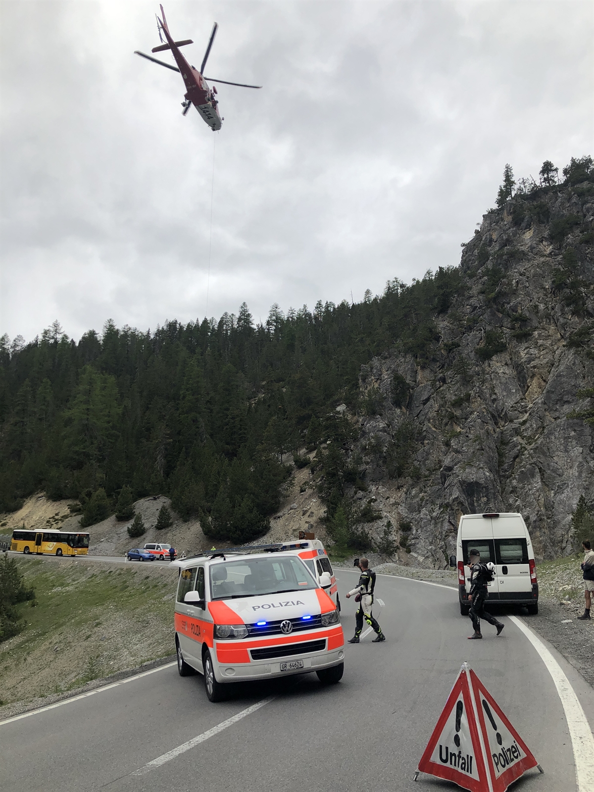 Bergungsaktion des verunfallten Motorradlenkers. Der Verletzte wird mit einer Windenaktion aus der Böschung geborgen. Polizei- und Ambulanzwagen im Vordergrund.