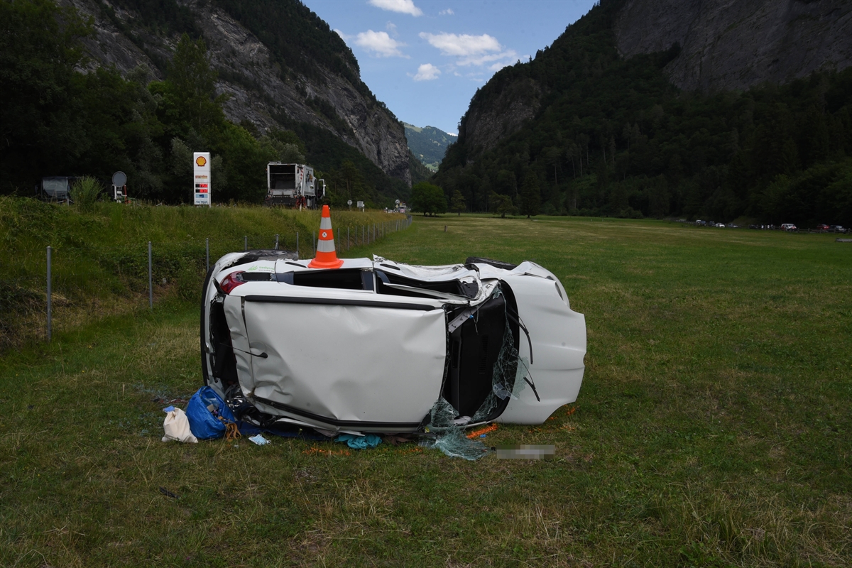 Personenwagen liegt seitlich in der Wiese