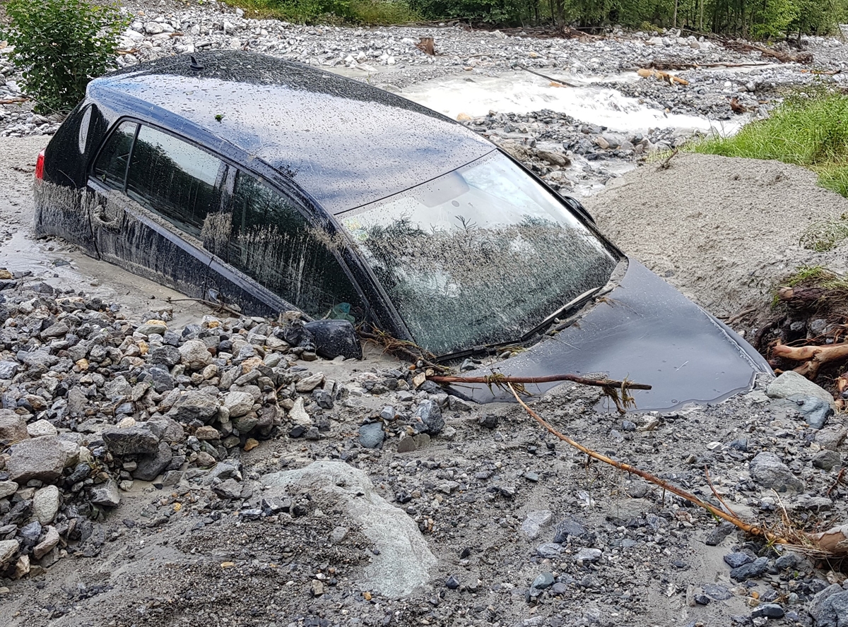 Das weggespülte Auto welches bis zur Hälfte im Geröll steck.